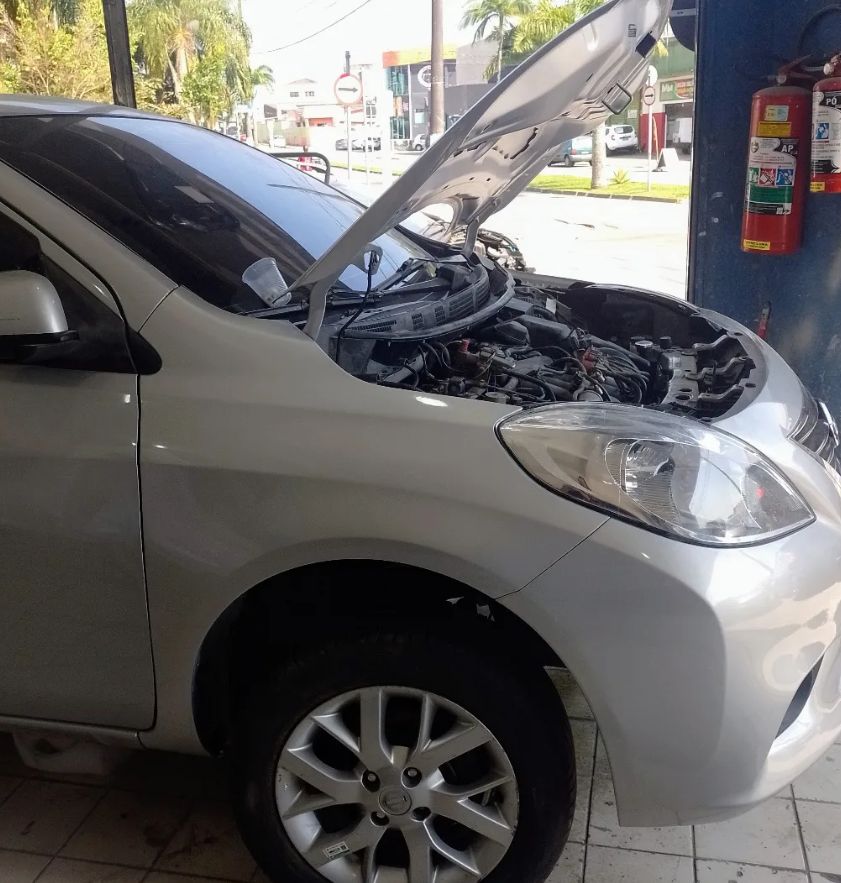 Nissan Versa com para-lama e farol novos no lugar, capô aberto durante a montagem