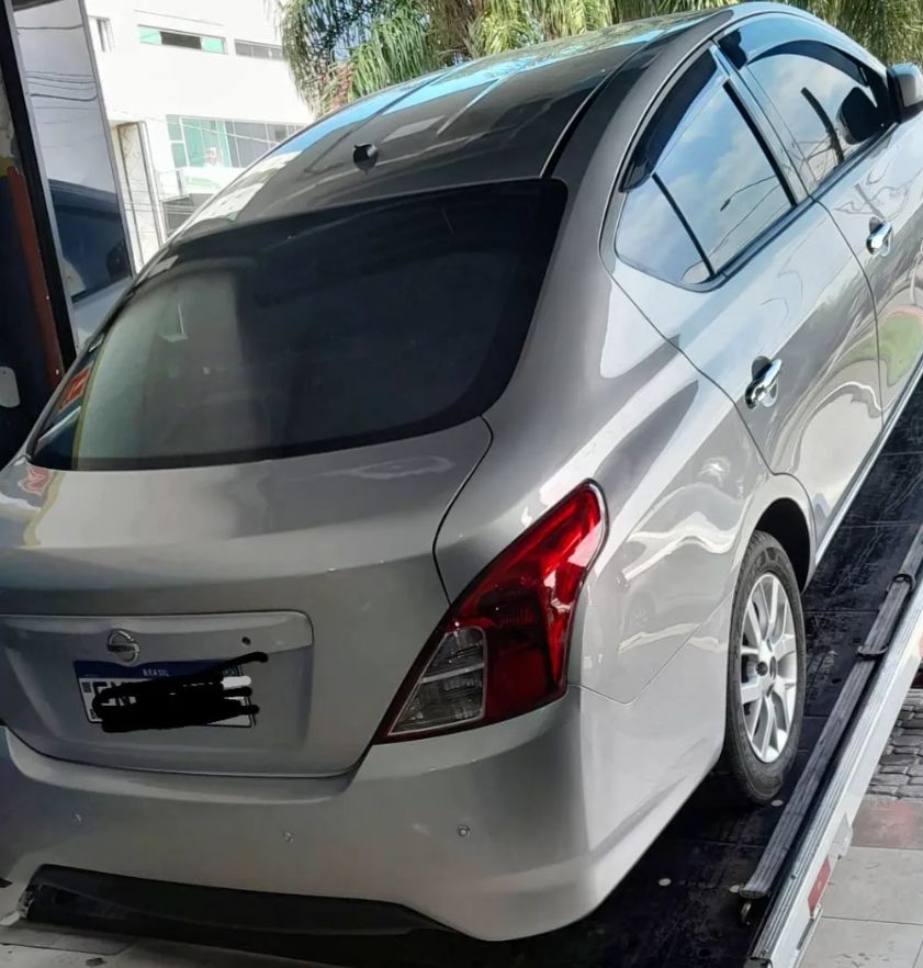 Traseira e lateral do Nissan Versa prata inteiras, com a pintura brilhando