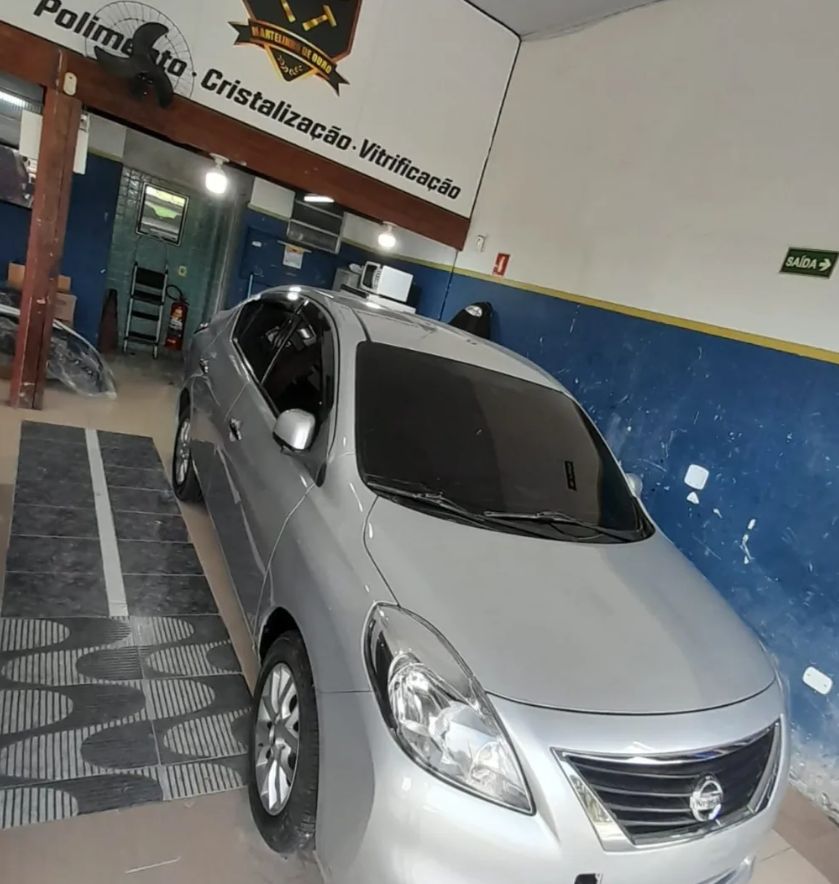 Nissan Versa prata pronto dentro da oficina, com a frente refeita
